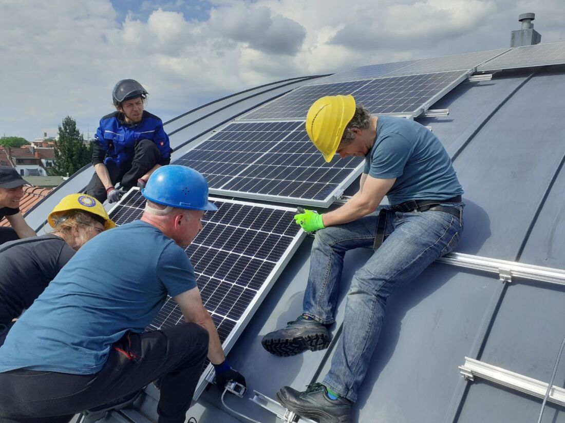 Mehrere Menschen arbeiten an den Solarpanelen